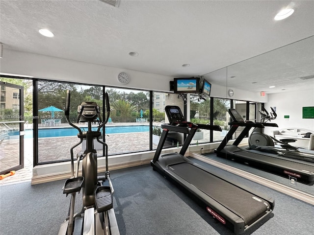 gym featuring a healthy amount of sunlight, a textured ceiling, and recessed lighting