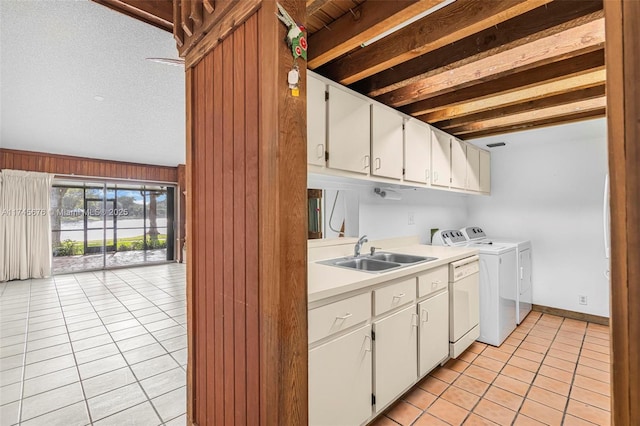 kitchen with white cabinetry, sink, light tile patterned floors, and washer and clothes dryer