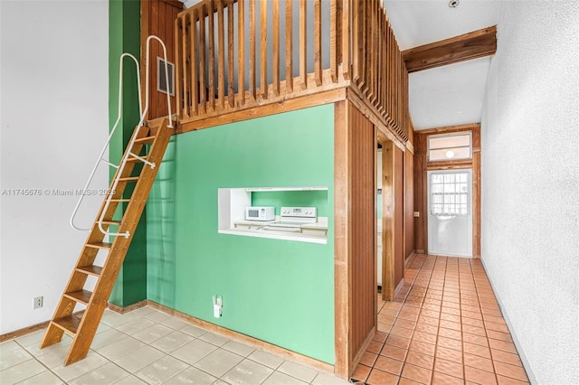 interior space with light tile patterned floors and beam ceiling