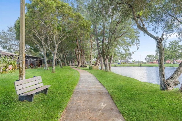 surrounding community with a water view and a yard