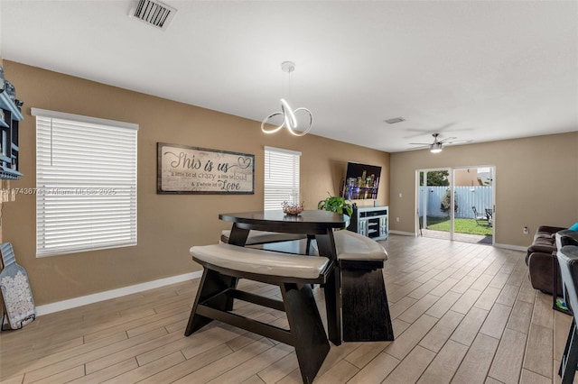 dining space featuring ceiling fan with notable chandelier and light wood-type flooring