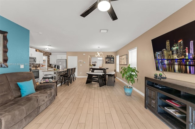 living room with ceiling fan and light wood-type flooring