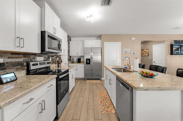 kitchen featuring white cabinetry, sink, a center island with sink, and appliances with stainless steel finishes