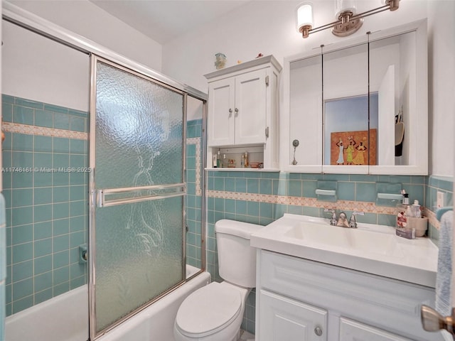 full bathroom featuring bath / shower combo with glass door, tile walls, decorative backsplash, vanity, and toilet