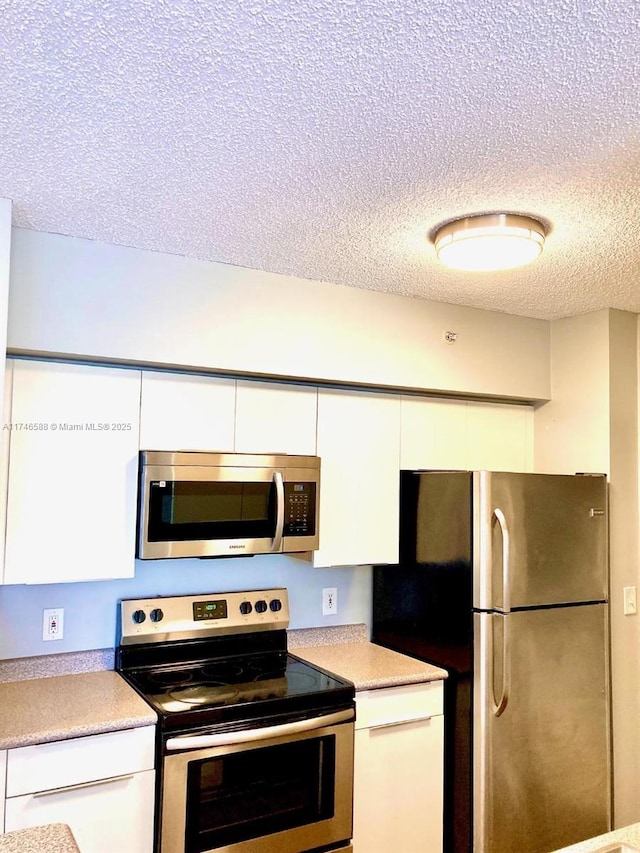 kitchen featuring white cabinetry, a textured ceiling, and appliances with stainless steel finishes