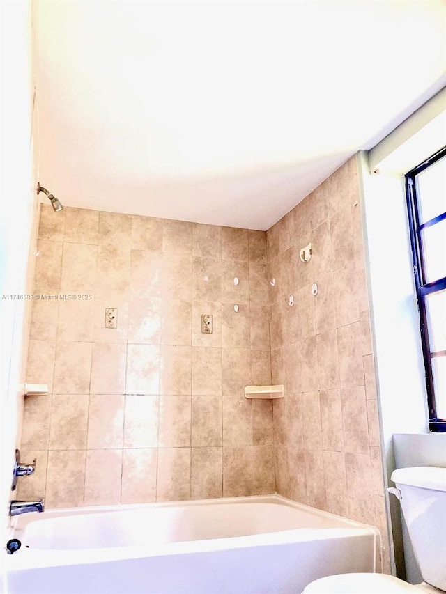 bathroom with tiled shower / bath and toilet