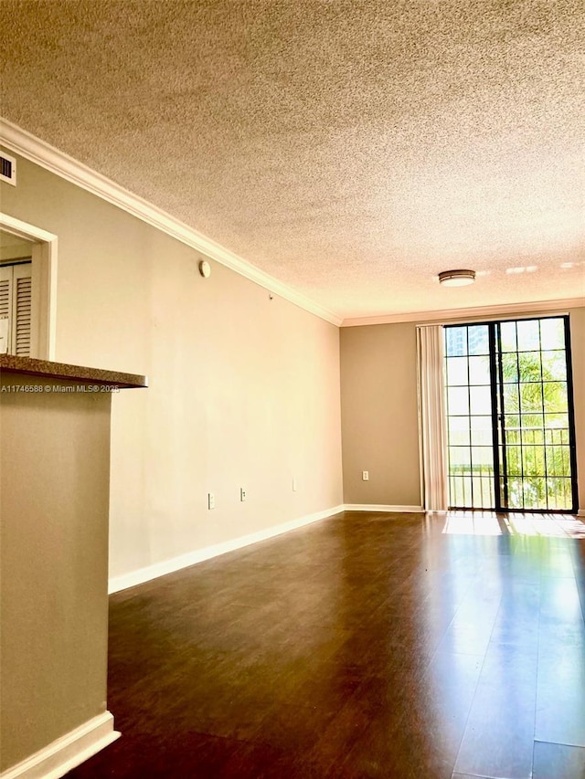 empty room with ornamental molding, dark hardwood / wood-style floors, and a textured ceiling