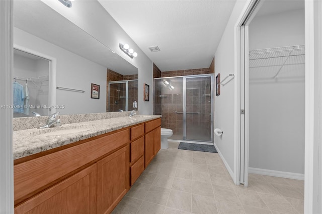 bathroom featuring double vanity, a shower stall, visible vents, and a sink