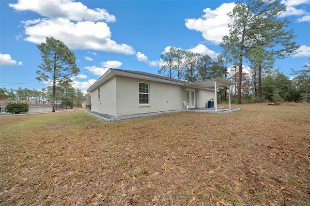 back of property with a patio area, a lawn, and stucco siding