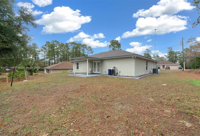 back of property featuring stucco siding, central AC unit, a lawn, and french doors