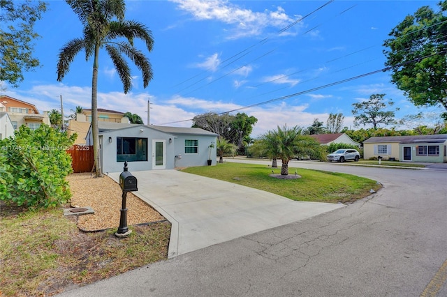 view of front facade featuring driveway, a front lawn, fence, and stucco siding