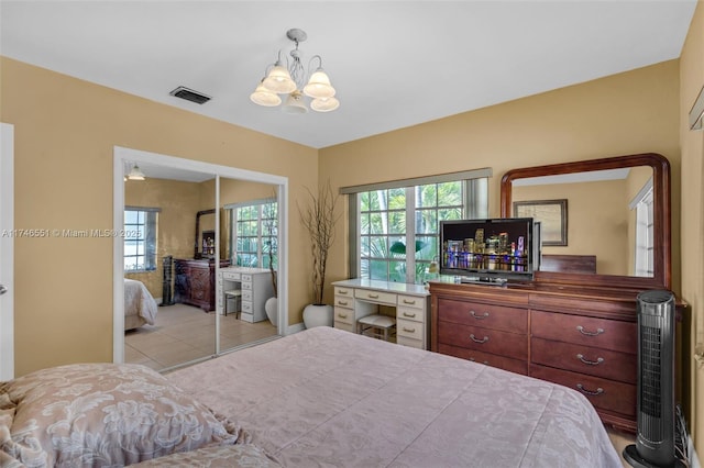 tiled bedroom featuring an inviting chandelier and a closet