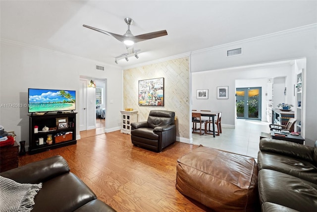 living room featuring ornamental molding, rail lighting, wood-type flooring, and ceiling fan