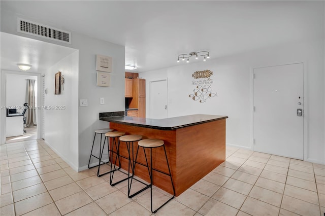 kitchen featuring kitchen peninsula, a breakfast bar area, and light tile patterned floors