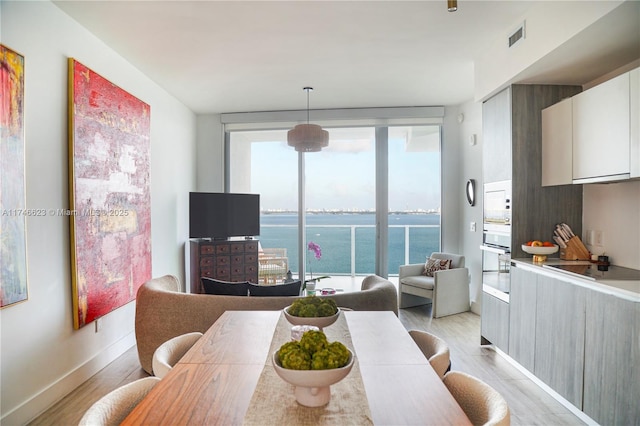 dining space with expansive windows, visible vents, light wood-style flooring, and baseboards