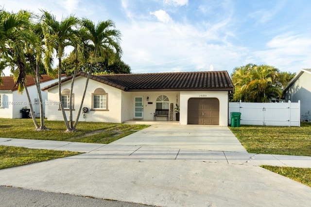 mediterranean / spanish-style home featuring a garage and a front lawn