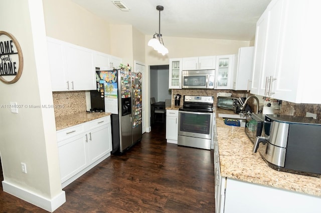 kitchen with lofted ceiling, sink, pendant lighting, stainless steel appliances, and white cabinets