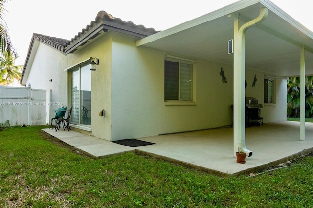 back of property featuring a patio and a lawn