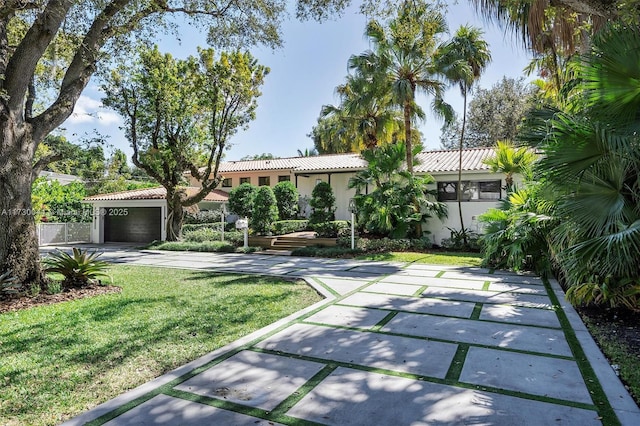 mediterranean / spanish-style home with fence, driveway, a tiled roof, stucco siding, and a front yard