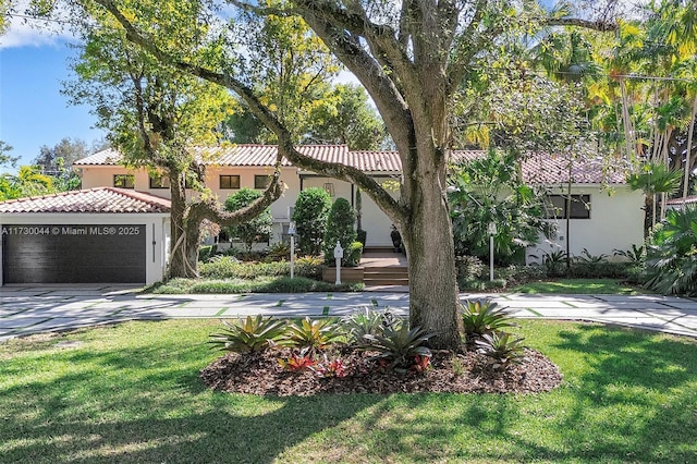 mediterranean / spanish-style house featuring concrete driveway, a front yard, a tile roof, and stucco siding