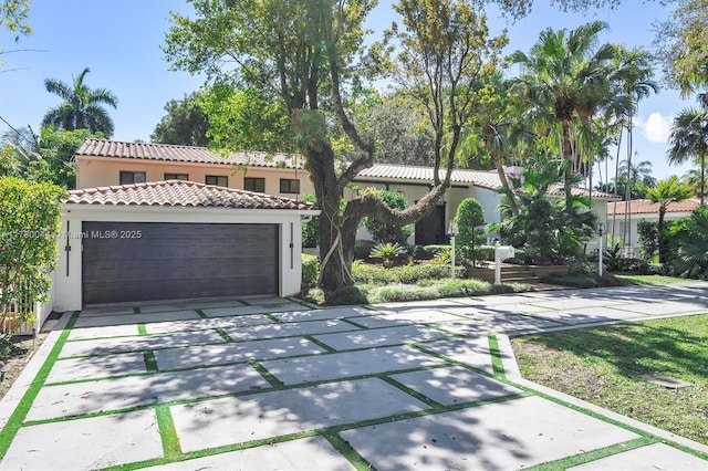 mediterranean / spanish-style home featuring concrete driveway, a tiled roof, an attached garage, and stucco siding