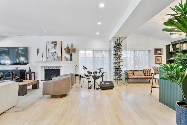 living room with recessed lighting, a fireplace with raised hearth, lofted ceiling, and wood finished floors