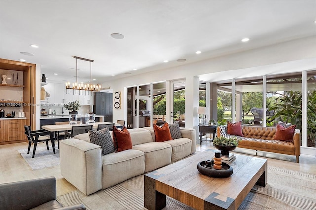 living area with light wood-style floors, recessed lighting, a chandelier, and french doors