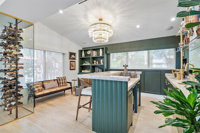 kitchen featuring lofted ceiling, light wood-type flooring, a kitchen island, and an inviting chandelier