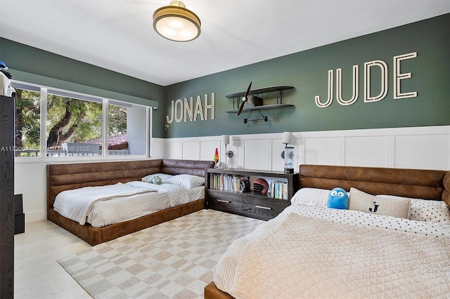 bedroom featuring a wainscoted wall and wood finished floors