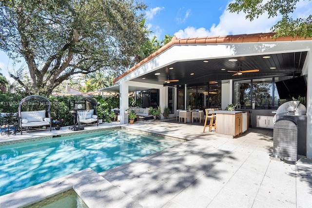 outdoor pool featuring a patio area, outdoor lounge area, ceiling fan, and an outdoor kitchen