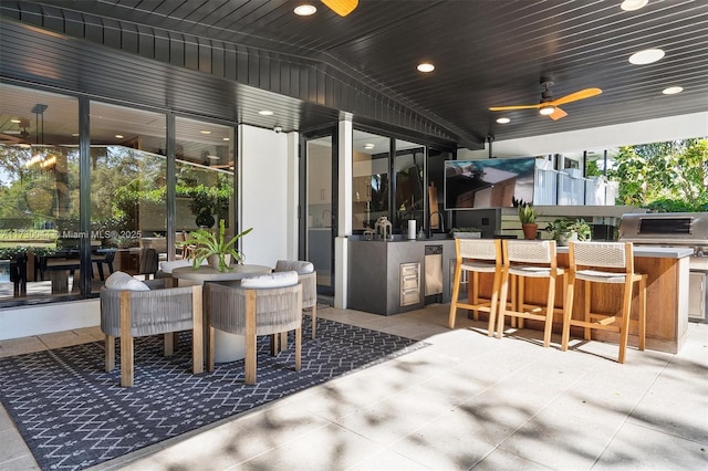 view of patio featuring exterior kitchen, outdoor dining area, a ceiling fan, and outdoor wet bar