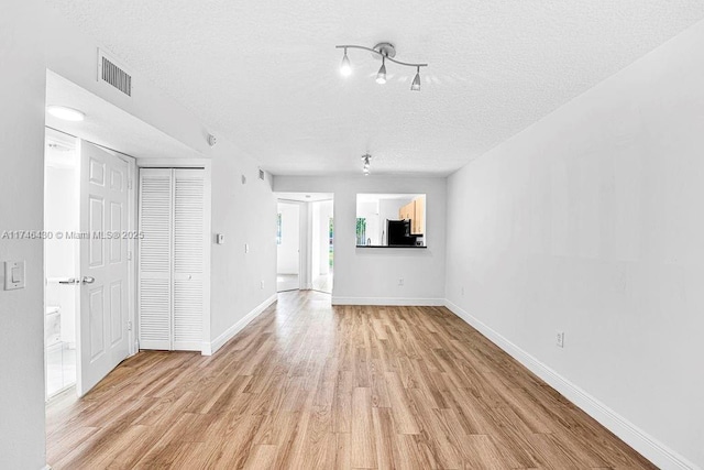 3505 Briar Bay Blvd Unit 104, West Palm Beach, FL 33411 - unfurnished living room with a textured ceiling, light wood-style flooring, and baseboards