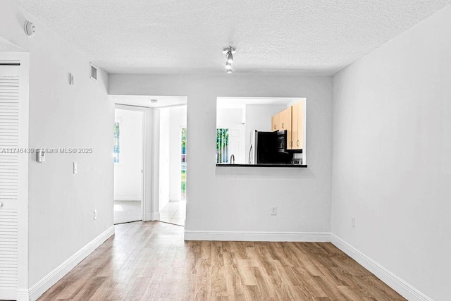 3505 Briar Bay Blvd Unit 104, West Palm Beach, FL 33411 - empty room with light wood-style floors, a textured ceiling, a smoke detector, and baseboards