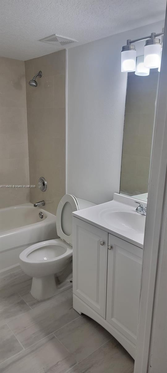 3505 Briar Bay Blvd Unit 104, West Palm Beach, FL 33411 - full bath with a textured ceiling, vanity, shower / bathtub combination, and toilet