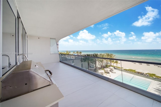 balcony with a view of the beach, sink, and a water view