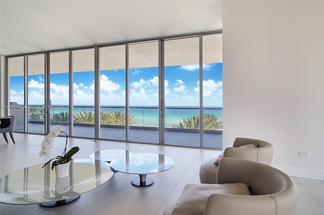 living room with a water view, floor to ceiling windows, and tile patterned flooring