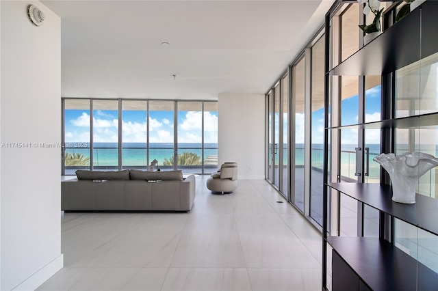 tiled living room with expansive windows, a water view, and a view of the beach