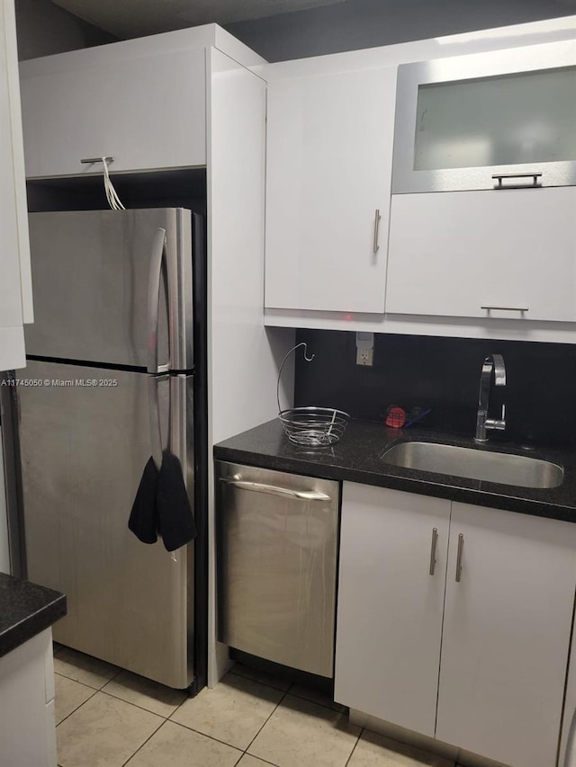 kitchen featuring dark countertops, appliances with stainless steel finishes, white cabinets, and a sink