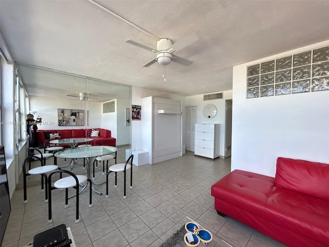 dining space with tile patterned flooring, a textured ceiling, visible vents, and a ceiling fan