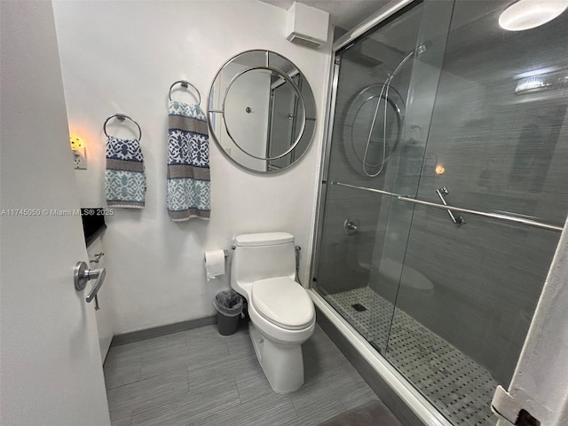 bathroom featuring baseboards, a shower stall, and toilet