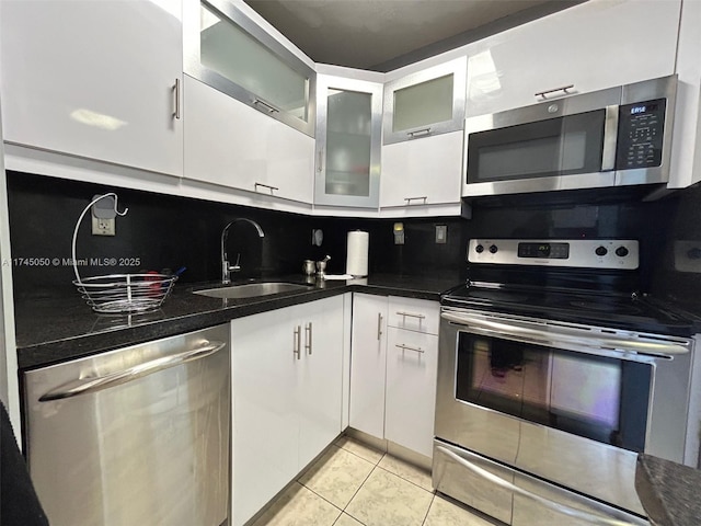 kitchen with stainless steel appliances, white cabinetry, glass insert cabinets, and a sink