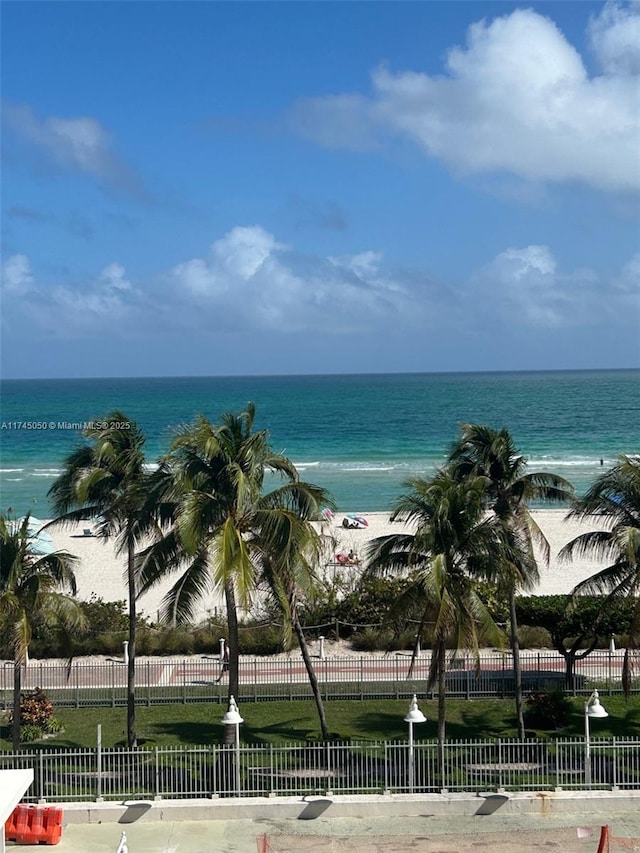 water view featuring fence and a beach view