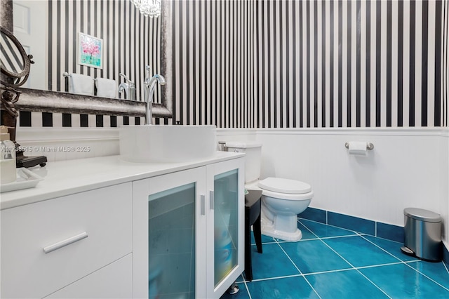 half bath featuring toilet, wallpapered walls, tile patterned floors, and vanity
