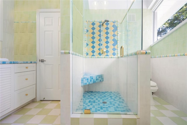 full bathroom featuring visible vents, toilet, tile walls, tile patterned floors, and a shower stall