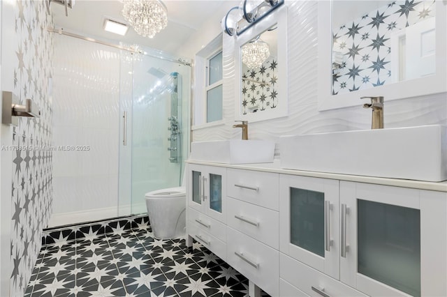 full bathroom with a sink, tile patterned floors, an inviting chandelier, and a shower stall