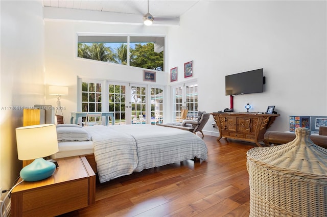bedroom with french doors, wood-type flooring, a high ceiling, and beamed ceiling