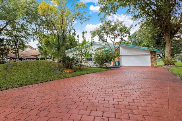 view of front of property with stone siding, an attached garage, decorative driveway, and a front yard