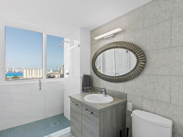 bathroom with walk in shower, vanity, toilet, and tile walls