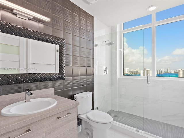 bathroom with a shower with door, tile walls, vanity, tasteful backsplash, and toilet