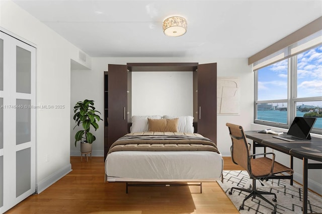 bedroom featuring hardwood / wood-style flooring and a water view